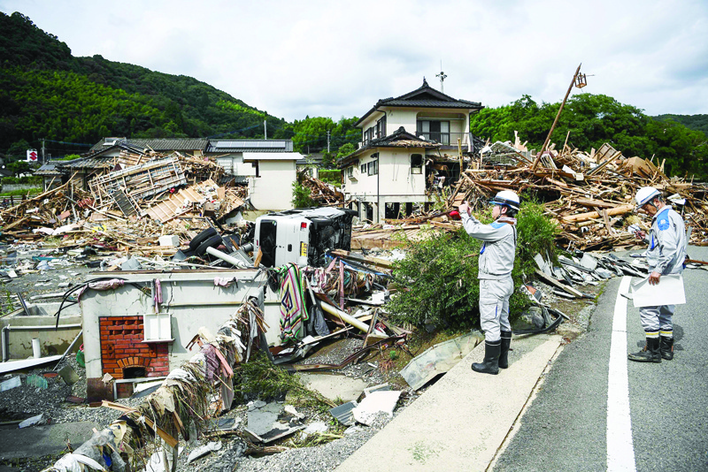 Workers survey the devastation following days of heavy rain and flooding in the village of Kuma, Kumamoto prefecture on July 8, 2020. - Torrential rain pounded central Japan on July 8 as authorities said 58 people were feared dead in days of heavy downpours that have triggered devastating landslides and terrifying floods around the country. (Photo by CHARLY TRIBALLEAU / AFP)
