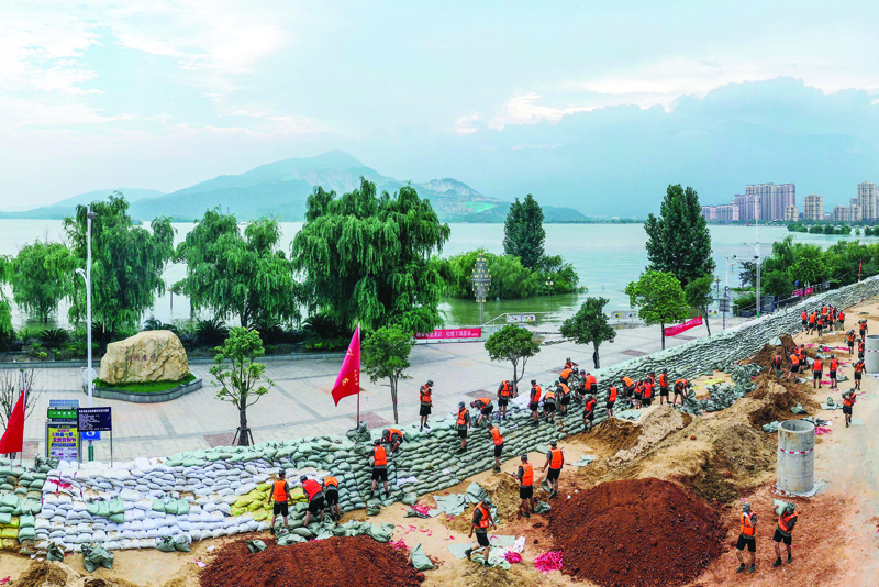 CORRECTION - This photo taken on July 13, 2020 shows Chinese soldiers building an emergency levee along the shore of Poyang lake to contain flooding due to seasonal rains and the swollen Yangtze River in Jiujiang in China's central Jiangxi province. - Floods across central and eastern China have left more than 140 people dead or missing and are swelling major rivers and lakes to record-high levels, with authorities warning that the worst was yet to come. (Photo by STR / AFP) / China OUT / ìThe erroneous mention[s] appearing in the metadata of this photo by STR has been modified in AFP systems in the following manner: [Poyang lake] instead of [Boyang lake]. Please immediately remove the erroneous mention[s] from all your online services and delete it (them) from your servers. If you have been authorized by AFP to distribute it (them) to third parties, please ensure that the same actions are carried out by them. Failure to promptly comply with these instructions will entail liability on your part for any continued or post notification usage. Therefore we thank you very much for all your attention and prompt action. We are sorry for the inconvenience this notification may cause and remain at your disposal for any further information you may require.î