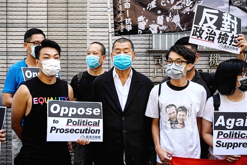 HONG KONG: Millionaire media tycoon Jimmy Lai (center), and other supporters and activists, who led the June 4 candlelight vigil which commemorates the 1989 Tiananmen Square crackdown in Beijing, gather before attending a mention at the West Kowloon Magistrates Court in Hong Kong yesterday. — AFP