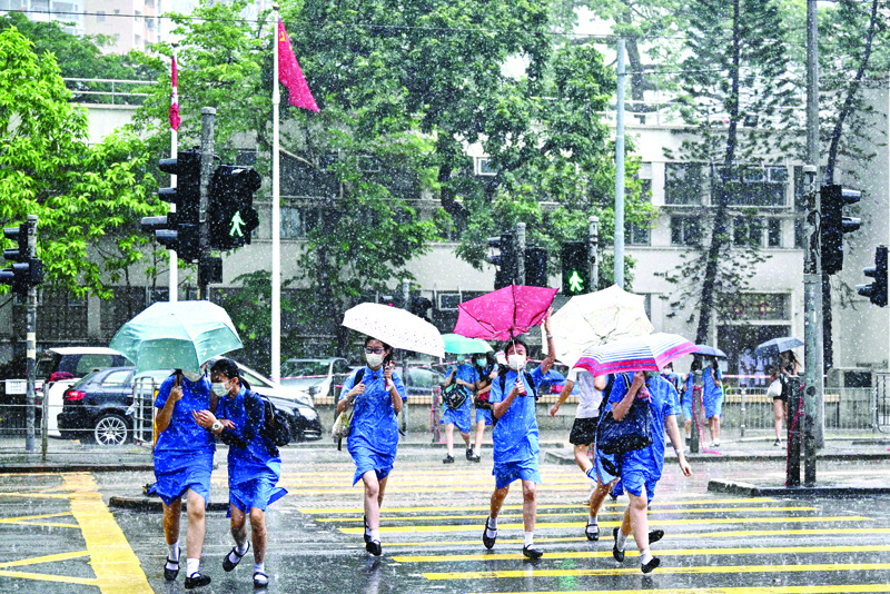 Students run for shelter during a sudden but brief heavy downpour in Hong Kong on July 8, 2020. (Photo by Anthony WALLACE / AFP)