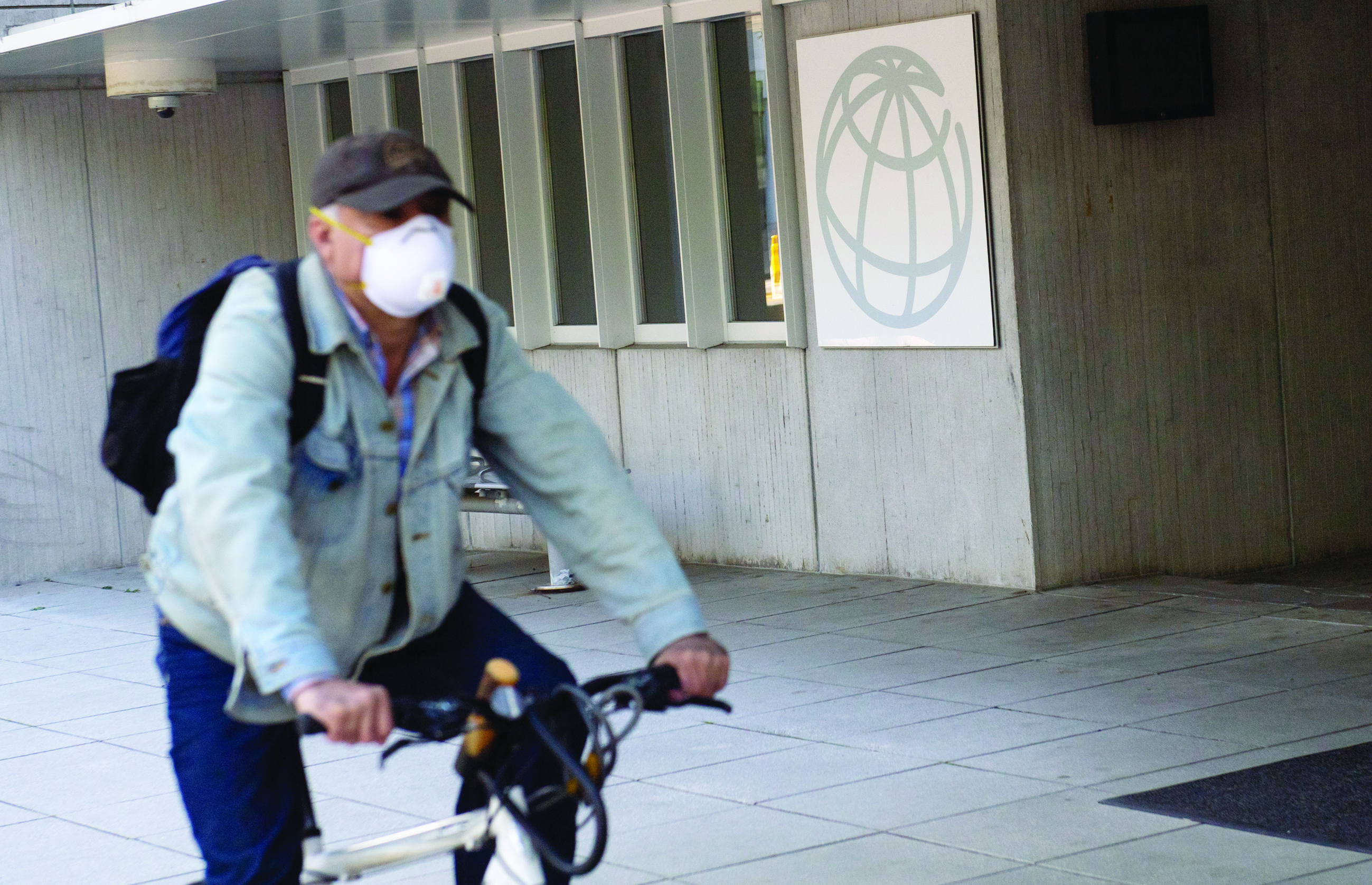 (FILES) In this file photo taken on April 15, 2020 a man rides a bicycle past the headquarters of the World Bank Group as the International Monetary Fund (IMF) and World Bank hold their Spring Meetings virtually due to the outbreak of COVID-19, known as coronavirus, in Washington, DC. - Despite some signs of recovery, the global economy faces continued challenges, including the possibility of a second wave of COVID-19, and governments should keep their support programs in place, IMF chief Kristalina Georgieva said July 16, 2020. (Photo by SAUL LOEB / AFP)