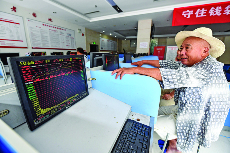 An investor looks at screens showing stock market movements at a securities company in Fuyang in China's eastern Anhui province on July 6, 2020. - Shanghai stocks surged on July 6 to a more than two-year high as investors piled in following a combination of rosy predictions for the market and strong economic data. (Photo by STR / AFP) / China OUT