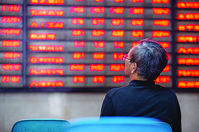 NANJING: An investor looks at screens showing stock market movements at a securities company in Nanjing in China’s eastern Jiangsu province. —AFP