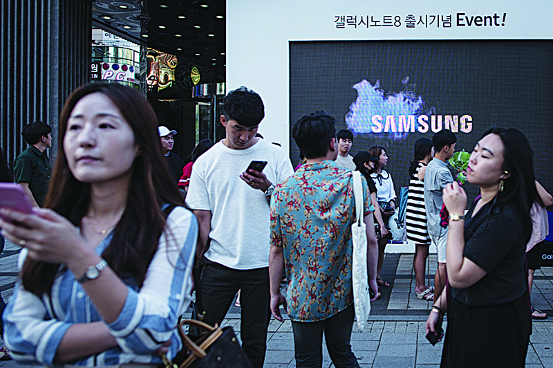 SEOUL: Pedestrians passing a Samsung promotional event outside a store in Seoul. Samsung Electronics forecast a 23-percent rise in second-quarter operating profit yesterday. —AFP