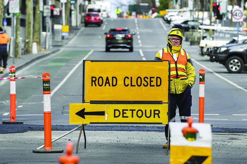 MELBOURNE: A worker stands beside a road sign in Melbourne yesterday. Australia will extend record stimulus spending into next year, the government announced yesterday, outlining multi-billion-dollar measures to shield the labor market from the ravages of the rolling coronavirus crisis. — AFP