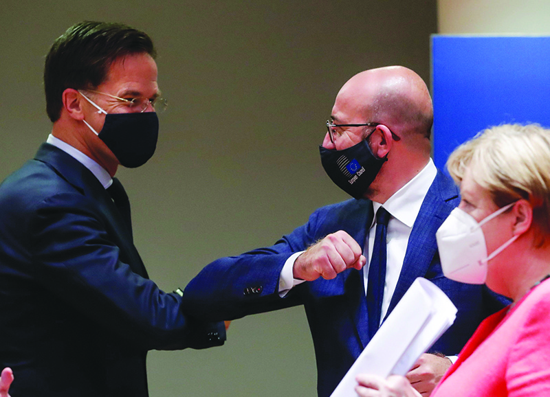 BRUSSELS: Dutch Prime Minister Mark Rutte (left) bumps elbows with European Council President Charles Michel as German Chancellor Angela Merkel watches at the European Council yesterday. — AFP