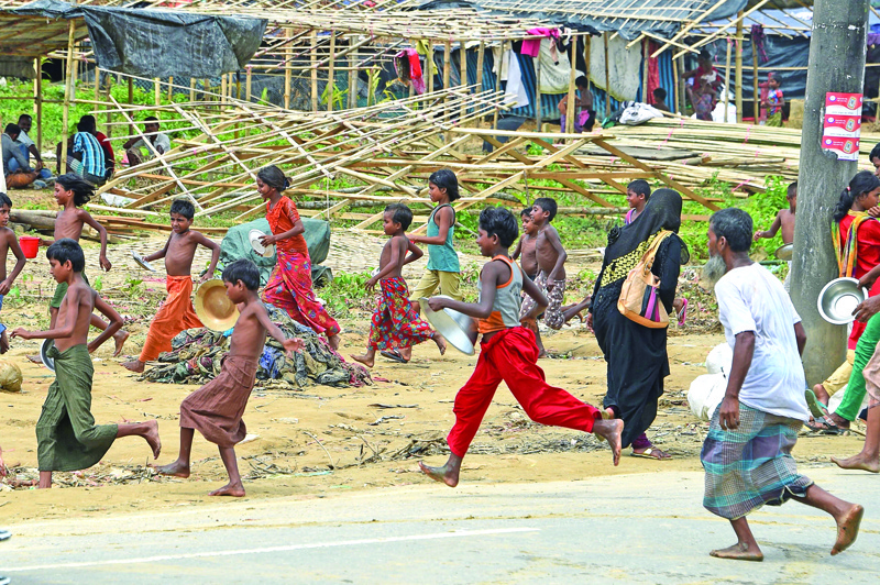 (FILES) In this file photograph taken on September 27, 2017, Rohingya refugees run for food being distributed at the Thangkhali refugee camp near Ukhia. - Nearly one in nine people in the world are going hungry, with the coronavirus pandemic exacerbating already worsening trends this year, according to a United Nations report published on July 13, 2020. Economic slowdowns and climate-related shocks are pushing more people into  hunger, while nutritious foods remain too expensive for many, the report found. (Photo by DOMINIQUE FAGET / AFP)