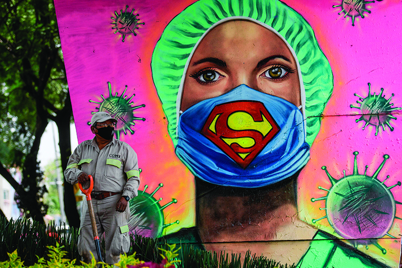 MEXICO CITY: A city gardener works next to a mural showing a health worker wearing a facemask with the symbol of fictional superhero Superman on Tuesday, amid the novel coronavirus pandemic. — AFP