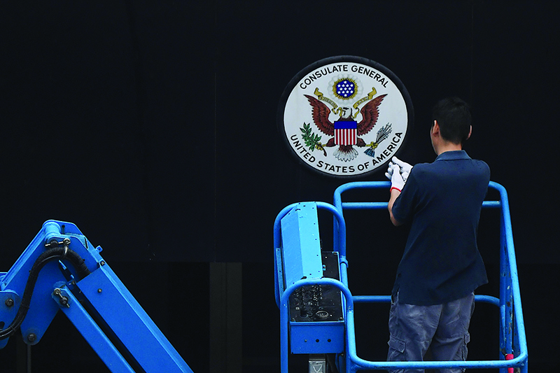 CHENGDU, China: A worker removes the sign at the entrance to the US consulate yesterday. — AFP
