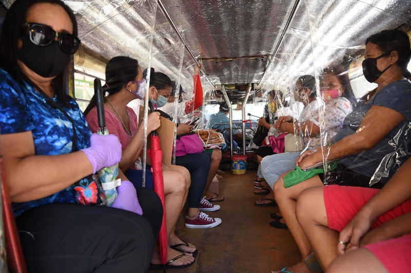 Passengers travel on a jeepney with seat dividers to ensure social distancing in Manila on July 6, 2020, after thousands of jeepneys hit the road again after over three months since they were forced to stop operation amid the COVID-19 coronavirus pandemic. (Photo by Ted ALJIBE / AFP)