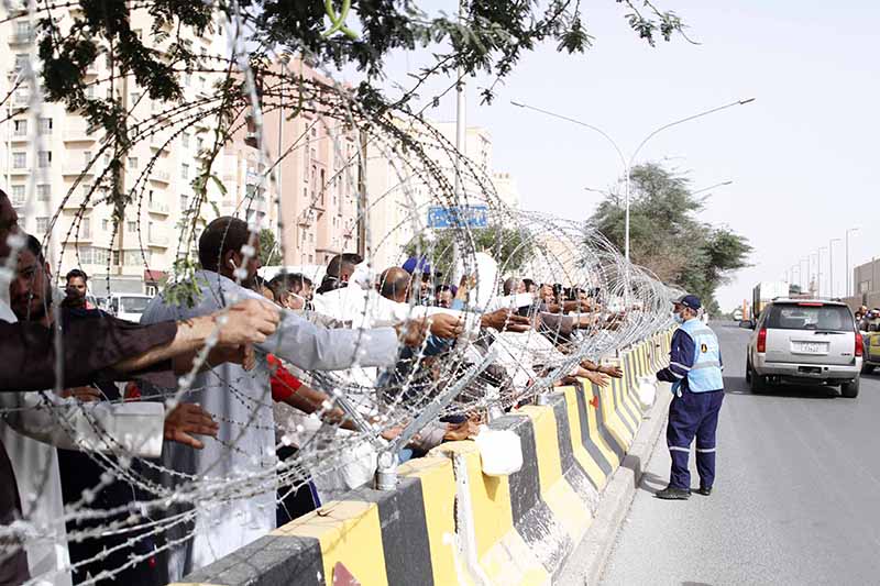 KUWAIT: This May 3, 2020 file photo shows a Civil Defense worker distributing food to people under lockdown in Jleeb Al-Shuyoukh. — Photo by Fouad Al-Shaikh