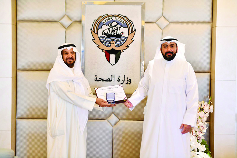 KUWAIT: Health Minister Sheikh Dr Basel Al-Sabah (right) honors Secretary General of Kuwait Society for Preventing Smoking and Cancer Anwar Burhama. — KUNA