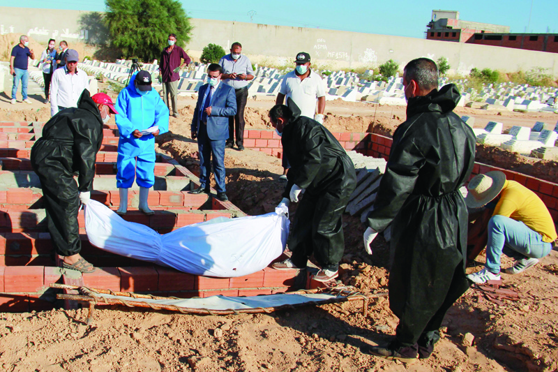 Gravediggers at a cemetery near the coastal city of Sfax, wear protective outfits as they carry out the burial of one of the 52 African migrants, who died at sea when their boat capsized near Tunisia's Kerkennah islands, on June 15, 2020. - The identity of dozens of migrants who drowned off Tunisia last month might have been lost without a trace, like thousands of others who have disappeared on the treacherous sea route to Europe.nBut when authorities recovered 61 bodies near the eastern port city of Sfax, they carefully took note of any details that could one day help lead to their identification. (Photo by Hamdi ZAGHDANE / AFP)