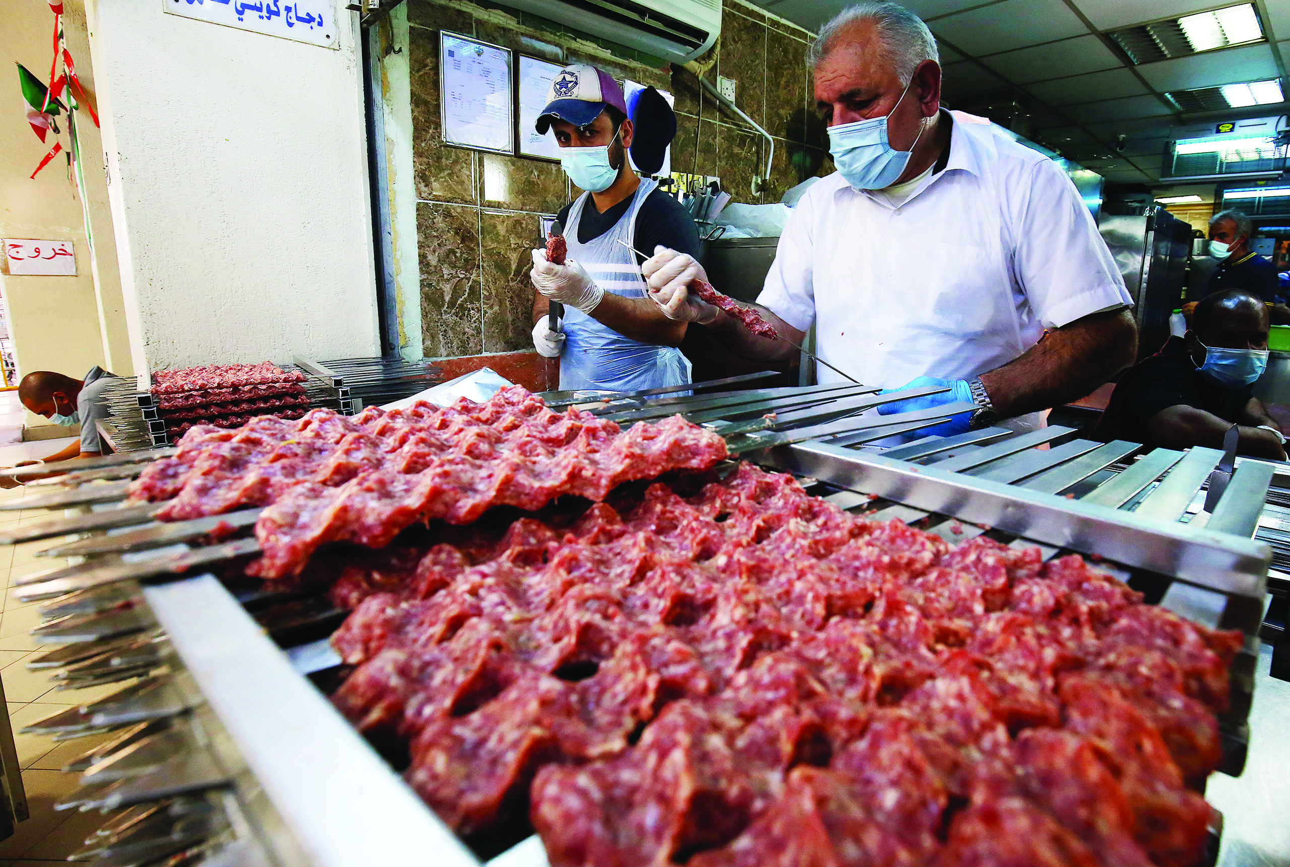 Food vendors wearing face masks prepare kebabs at a market in Kuwait City, on July 20, 2020 amid the Covid-19 coronavirus pandemic crisis. (Photo by YASSER AL-ZAYYAT / AFP)
