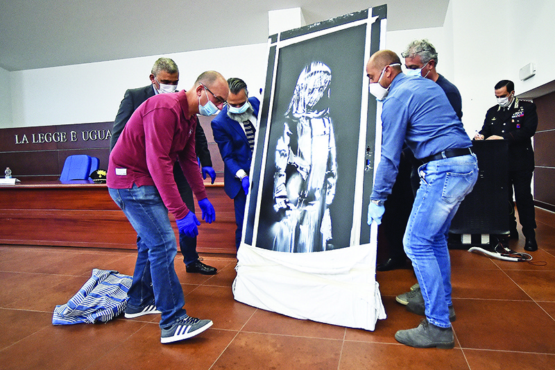 In this file photo Men unveil a piece of art attributed to Banksy.