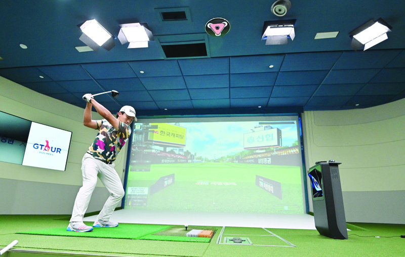 This photo taken on July 24, 2020 shows a South Korean golfer hitting a ball in a simulation booth during the GTour screen golf tournament in Daejeon, south of Seoul. - The popularity of screen golf in South Korea is driven by accessibility: with more than 65 percent of the country made up of mountains and a population of 52 million, land for golf courses is at a premium, club memberships are highly exclusive, and green fees can cost hundreds of dollars. (Photo by Jung Yeon-je / AFP)