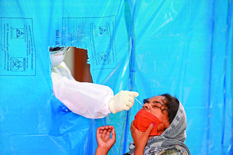 A health worker wearing Personal Protective Equipment (PPE) suit collects a swab sample of a resident at a free testing centre for the COVID-19 coronavirus, in Hyderabad on July 27, 2020. (Photo by NOAH SEELAM / AFP)