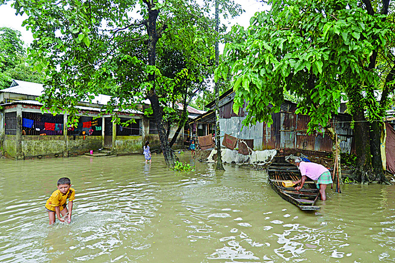 SUNAMGONG: A man works on a boat as a boy walks through flood waters in Sunamgong yesterday. Almost four million people have been hit by monsoon floods in South Asia, officials said, with a third of Bangladesh already underwater from some of the heaviest rains in a decade. —AFP