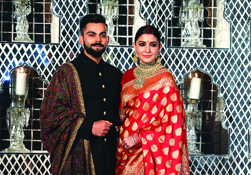 (FILES) In this file photo taken on December 21, 2017, Indian cricketer Virat Kohli (L) and Bollywood actress Anushka Sharma, who were recently married in Italy, pose during a reception in New Delhi. - Indian cricketing star Kohli on August 27 announced that he and his Bollywood actress wife Anushka are expecting their first child in January next year. (Photo by PRAKASH SINGH / AFP)