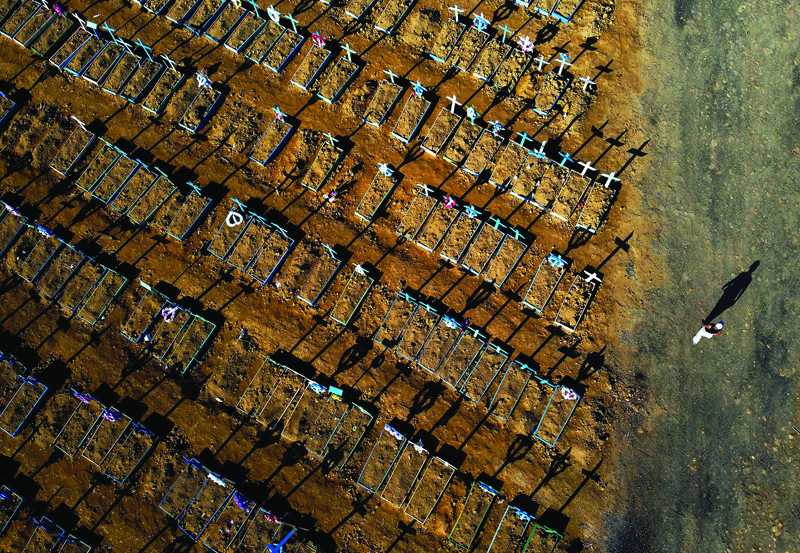 (FILES) This file photo taken on June 21, 2020 shows an aerial view of a man walking past graves in the Nossa Senhora Aparecida cemetery in Manaus on June 21, 2020. - Just over six months after registering its first case of the new coronavirus, Brazil -a country of 212 million people- has now registered 120,262 deaths from the virus and 3,846,153 infections, the health ministry said in its daily update. (Photo by MICHAEL DANTAS / AFP)