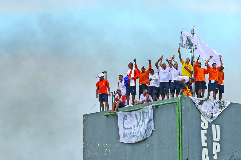 (FILES) In this file photo taken on May 02, 2020 inmates are seen on the top of a tower of the Puraquequara prison during a rebellion to demand better conditions inside the prison in which seven guards were taken hostage, in Manaus, Amazona State, Brazil, amid the novel coronavirus pandemic. - The precarious and overcrowded prisons of Brazil added up a new evil: the new coronavirus pandemic, which deepened the deficiencies of healthcare services and left prisoners more isolated than even from their families. (Photo by Michael DANTAS / AFP)