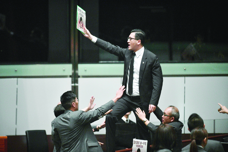 (FILES) In this file photo taken on October 16, 2019, pro-democracy lawmaker Lam Cheuk-ting (C) stands up and protests shortly before Hong Kong's Chief Executive Carrie Lam (not pictured) leaves the chamber for the second time while trying to present her annual policy address at the Legislative Council (Legco) in Hong Kong. - Two prominent Hong Kong opposition lawmakers were arrested early on August 26, 2020 in a police operation focused on last year's huge anti-government protests, the latest move in a widening crackdown against the city's democracy camp. (Photo by ANTHONY WALLACE / AFP)