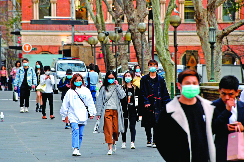 People wearing face masks walk on a street in the central business district of Sydney on August 3, 2020. - Australia's total reported infections of the COVID-19 coronavirus reached almost 18,000 in a population of 25 million. (Photo by Saeed KHAN / AFP)