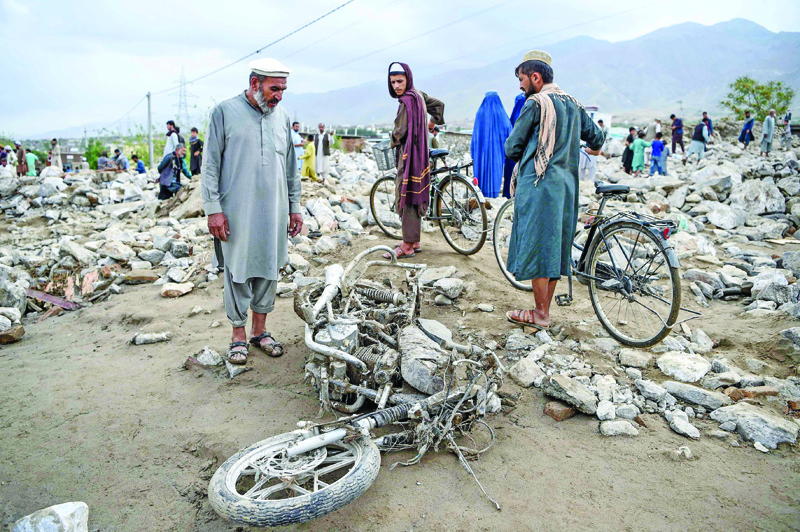 TOPSHOT - A villager (L) stands next to a destroyed motorbike as residents gather among the debris of their houses after a flash flood affected the area at Sayrah-e-Hopiyan in Charikar, Parwan province, on August 26, 2020. - The death toll from flash floods that swept through an Afghan city climbed to 100 on August 26, officials said, as rescue workers searched for survivors in the rubble of collapsed houses. (Photo by WAKIL KOHSAR / AFP)