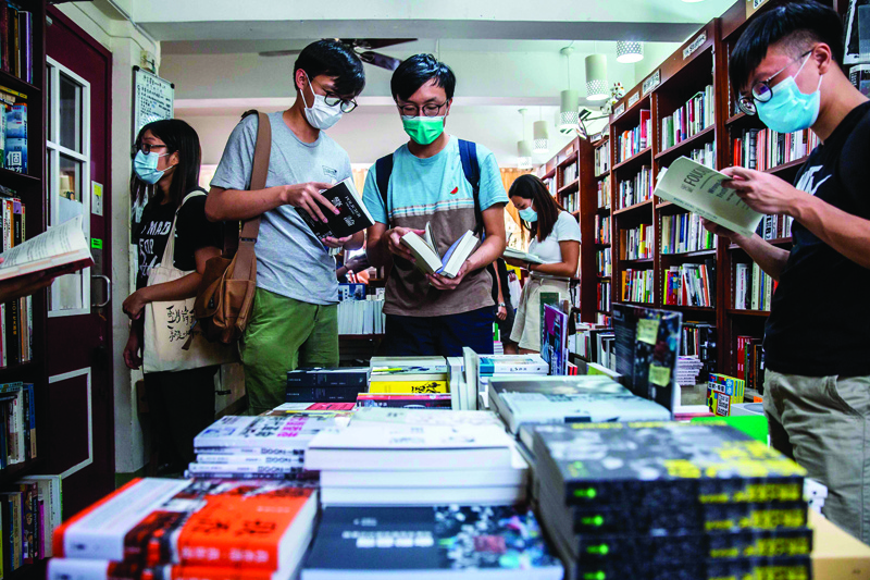 This picture taken on July 25, 2020 shows customers browsing in a bookstore in Hong Kong that stocks books with sensitive political titles that could potentially contravene the new national security law. - China's new security law in Hong Kong has sent a chill through the city's rambunctious book industry, with authors and publishers revisiting catalogues and some looking to Taiwan to print potentially now subversive titles. (Photo by ISAAC LAWRENCE / AFP) / TO GO WITH HongKong-China-politics-books,FOCUS by Su Xinqi