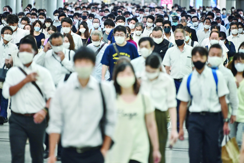 People commute early morning in Tokyo on August 17, 2020. - Japan's economy shrank a historic 7.8 percent in the April-June quarter, the worst contraction in the nation's modern history, as the coronavirus deepens the country's economic woes. (Photo by Charly TRIBALLEAU / AFP)