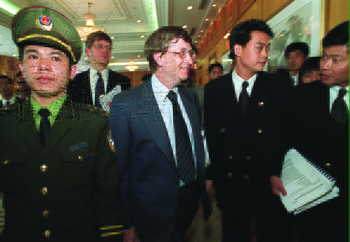 (FILES) This file photo taken on March 10, 1999 shows Microsoft then-chief executive Bill Gates (C) walking among heavy security inside a hotel lobby during a visit to Shenzhen in southern China's Guangdong province. - Computer giant Microsoft -- in talks to buy Chinese video app TikTok on August 5, 2020 -- is one of few US internet companies to succeed in China, despite the Communist nation's wide-reaching censorship. Microsoft's founder Bill Gates has long embodied a model of success in the eyes of many Chinese people and his books are bestsellers in the country. (Photo by Frederic J. BROWN / AFP)