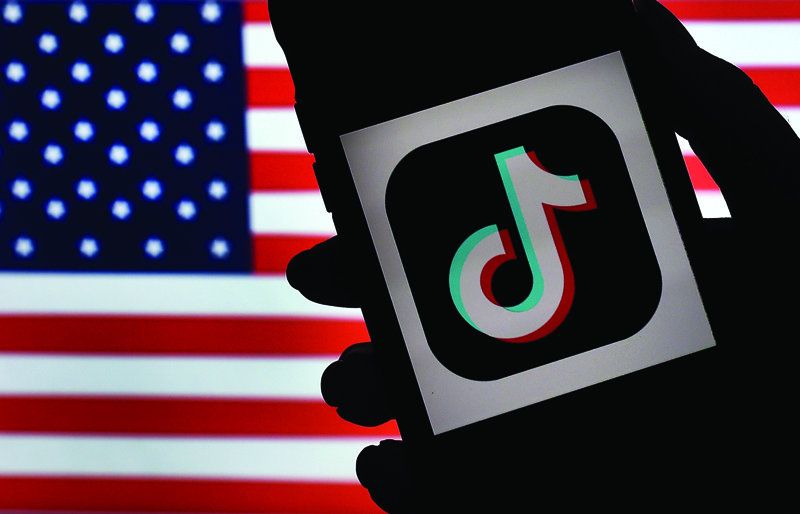 (FILES) In this file illustration photo taken on August 3, 2020  the social media application logo TikTok is displayed on the screen of an iPhone on an American flag background in Arlington, Virginia. - The US is expanding its China-targeted Clean Network program to include Chinese-made cellphone apps and cloud computing services that it claims are security risks, Secretary of State Mike Pompeo announced on August 5, 2020. (Photo by Olivier DOULIERY / AFP)