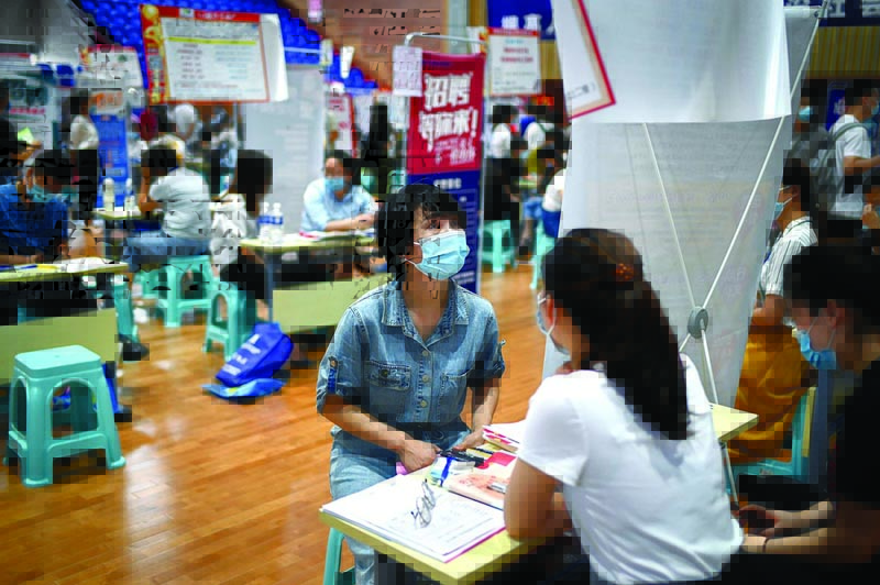 A job seeker (L) interacts with a hiring official of a company during a career fair in Zhengzhou, China's Henan province on July 25, 2020. (Photo by WANG Zhao / AFP)