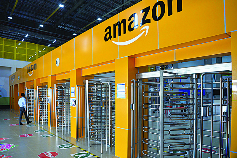 (FILES) In this file photo taken on September 18, 2018, an employee of Amazon India walks towards a security gate at Amazon's newly launched fulfilment centre situated on the outskirts of Bangalore. - US tech giant Amazon launched its first Indian online pharmacy service on Friday as it attempts to grab more of the country's burgeoning e-commerce market. (Photo by MANJUNATH KIRAN / AFP)