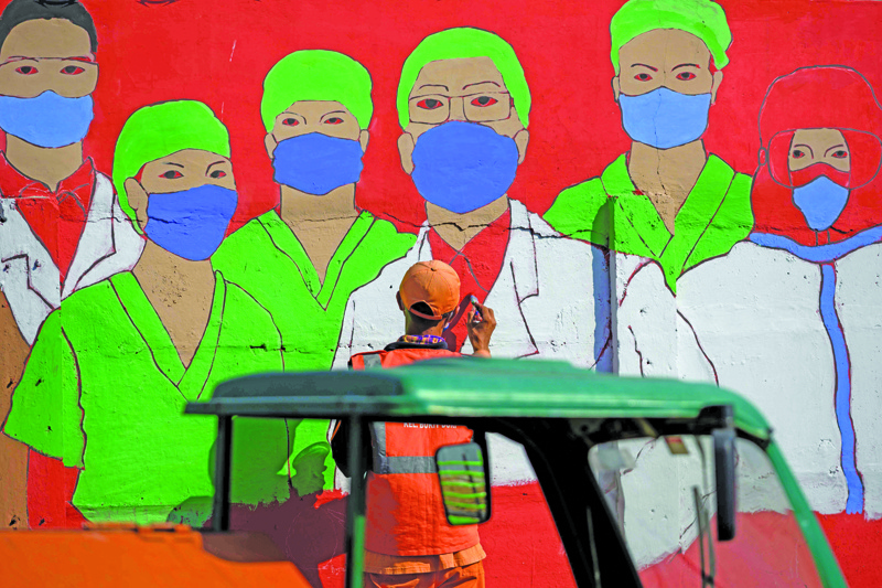 A city worker draws a mural campaigning against the COVID-19 coronavirus on a wall in Jakarta on August 27, 2020. - Indonesia had reported over 150,000 coronavirus cases and 6,858 deaths, but with some of the world's lowest testing rates the true scale is widely believed to be much greater. (Photo by Bay ISMOYO / AFP)