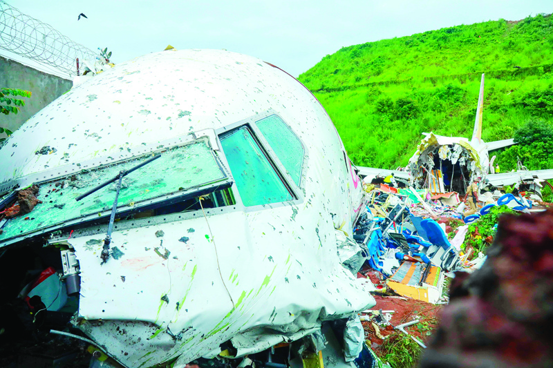 TOPSHOT - Officials inspect the wreckage of an Air India Express jet at Calicut International Airport in Karipur, Kerala, on August 8, 2020. - Fierce rain and winds lashed a plane carrying 190 people before it crash-landed and tore in two at an airport in southern India, killing at least 18 people and injuring scores more, officials said on August 8. (Photo by Arunchandra BOSE / AFP)