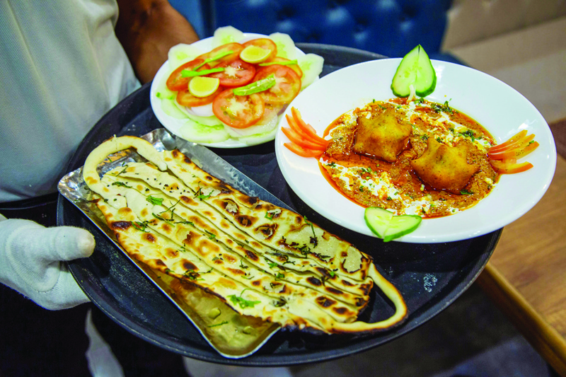 TOPSHOT - A waiter carries 'Covid Curry' and 'Mask Naan,' two Covid-19 coronavirus-themed dishes, to serve to customers at their restaurant in Jodhpur on August 3, 2020. (Photo by SUNIL VERMA / AFP)