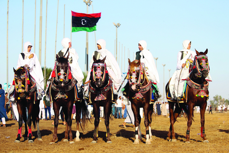Libyan men, wearing traditional costumes, ride horses during a popular equestrian festival near the capital Tripoli on August 21, 2020. (Photo by Mahmud TURKIA / AFP)
