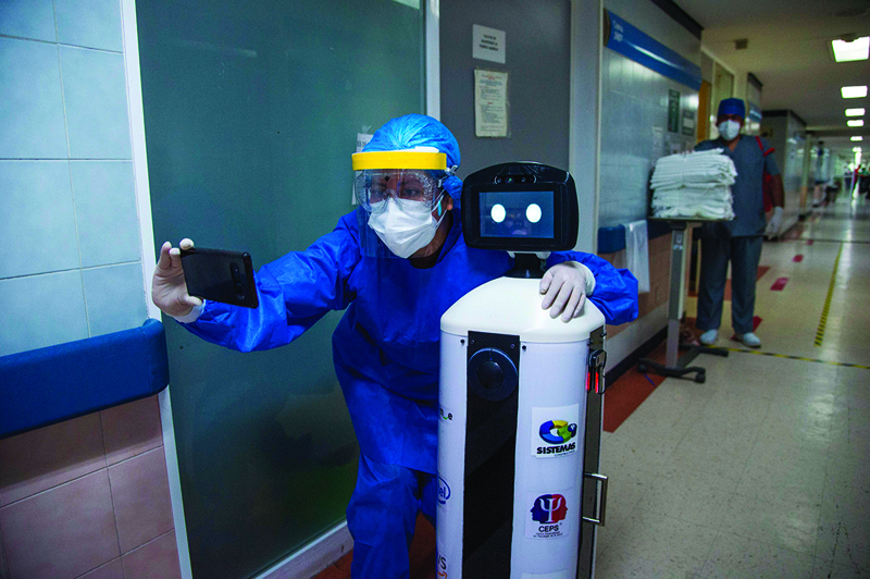TOPSHOT - A health worker makes a selfie with ìLaLuchy Robotinaî robot at the 20 de Noviembre National Medical Center in Mexico City, on August 27, 2020, amid the new coronavirus pandemic. - The robot helps health workers with consultations, therapies and mental health evaluations of COVID-19 patients, as part of the Psychiatry, Paidopsychiatry, Psychology and Neuropsychology service of the hospital. (Photo by CLAUDIO CRUZ / AFP)