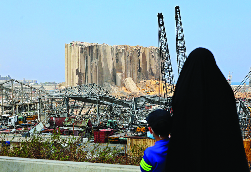 A woman with her boy contemplate the damaged grain silos at the port of Beirut following a huge explosion that disfigured the Lebanese capital, on August 12, 2020. - Survivors of Beirut's August 4 blast are still in shock over a disaster that disfigured their city. The earth-shaking explosion killed 171 people and wounded more than 6,000, a sickening blow to a country already in crisis. (Photo by Anwar AMRO / AFP)