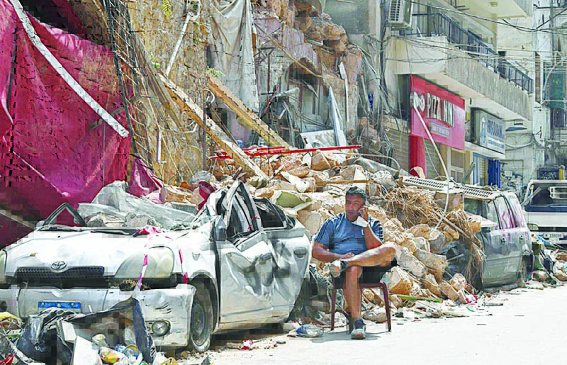TOPSHOT - A Lebanese man talks on the phone while seated by the rubble of a destroyed traditional building in the Gemmayzeh neighbourhood, on August 12, 2020, following last week's cataclysmic port explosion which devastated the capital Beirut. (Photo by - / AFP)