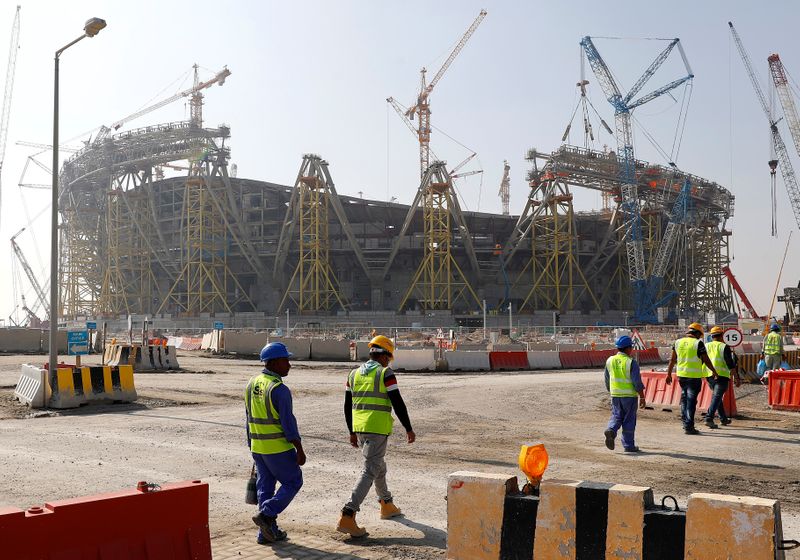 FILE PHOTO: Workers walk towards the construction site of the Lusail stadium which will be build for the upcoming 2022 Fifa soccer World Cup during a stadium tour in Doha, Qatar, December 20, 2019.  REUTERS/Kai Pfaffenbach