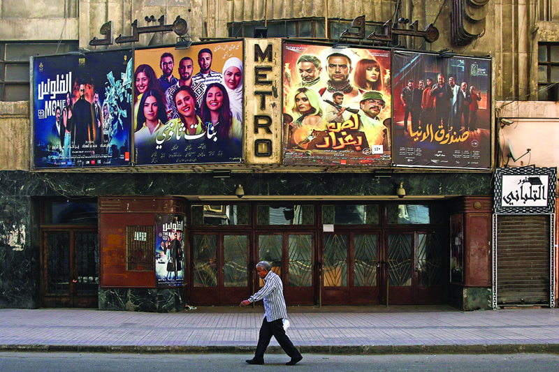 (FILES) This file picture taken early on May 24, 2020 shows a view of the historic Metro cinema theatre as a man walks past, along the commercial Talaat Harb street in the almost deserted city centre Egypt's capital Cairo, on the first day of Eid al-Fitr, the Muslim holiday which starts at the conclusion of the holy fasting month of Ramadan. - Egyptian cinemas are slowly reopening after months of lockdown, but the huge sector sometimes dubbed the Hollywood of the Arab world has taken a severe hit during the pandemic. After most studios, sets and movie theatres were shuttered because of COVID-19 from at least March to June, filmmakers and the wider sector are bracing for an uncertain future. (Photo by Samer ABDALLAH / AFP)