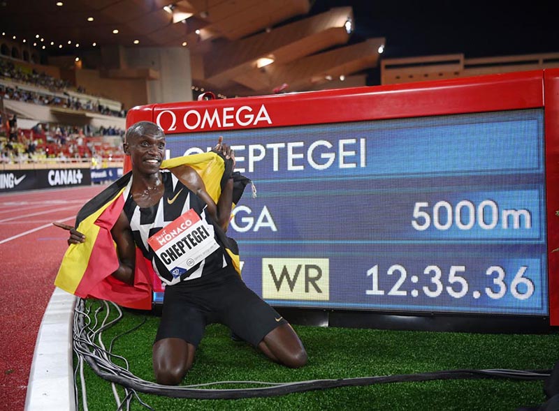 MONACO: Uganda’s Joshua Cheptegei, wearing an Uganda national flag on his shoulders, poses for pictures next to the timer screen after breaking the world record in the men’s 5000metre event during the Diamond League Athletics Meeting at The Louis II Stadium in Monaco. —AFP