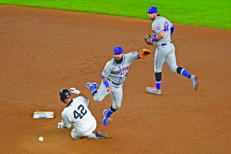 NEW YORK, NEW YORK - AUGUST 28: Gary Sanchez #42 of the New York Yankees slides into second as Luis Guillorme #42 of the New York Mets turns a double play during the third inning of the second game of a doubleheader at Yankee Stadium on August 28, 2020 in the Bronx borough of New York City. Jeff McNeil #42 of the New York Mets looks on. All players are wearing #42 in honor of Jackie Robinson Day. The day honoring Jackie Robinson, traditionally held on April 15, was rescheduled due to the COVID-19 pandemic.   Sarah Stier/Getty Images/AFP