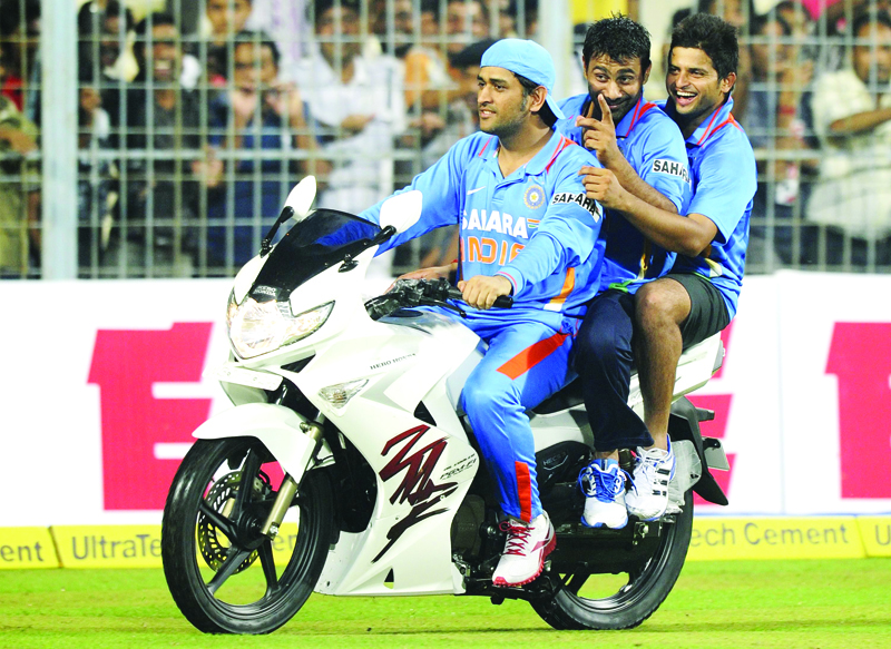 (FILES) In this file photo taken on October 25, 2011, Indian cricket captain Mahendra Singh Dhoni (L) rides a bike he won as the man of the tournament as teammate Praveen Kumar (C) and Suresh Raina ride with him after winning the final one day international (ODI) match between India and England at Eden Gardens Cricket Stadium in Kolkata. - M.S. Dhoni announced his retirement from India's national team on Saturday but the cricket legend will carry on playing in the Indian Premier League. Meanwhile Indian batsman and Dhoni's teammate in the Chennai team Suresh Raina also announced his international retirement. (Photo by Dibyangshu SARKAR / AFP)