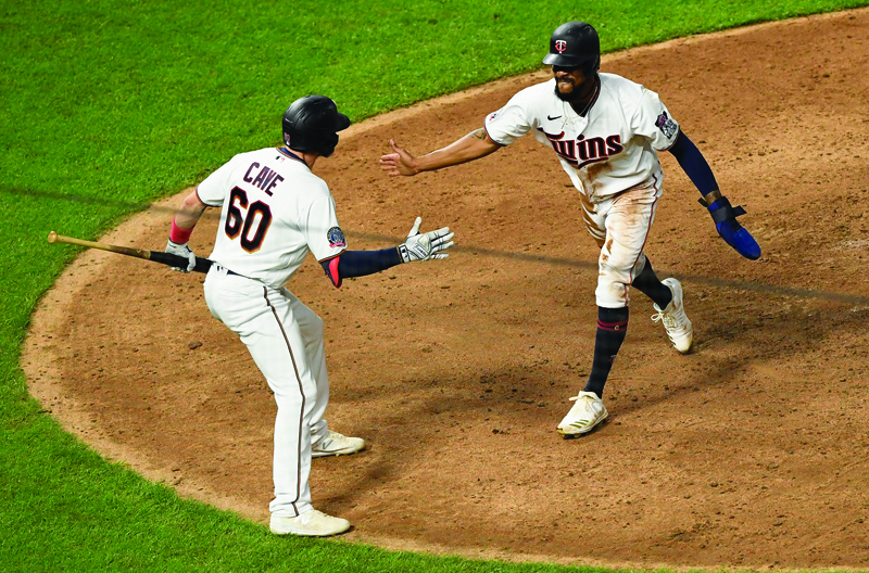 MINNEAPOLIS, MINNESOTA - AUGUST 18: Jake Cave #60 of the Minnesota Twins congratulates teammate Byron Buxton #25 on scoring the walk-off run against the Milwaukee Brewers during the twelfth inning of the game at Target Field on August 18, 2020 in Minneapolis, Minnesota. The Twins defeated the Brewers 4-3 in twelve innings.   Hannah Foslien/Getty Images/AFP