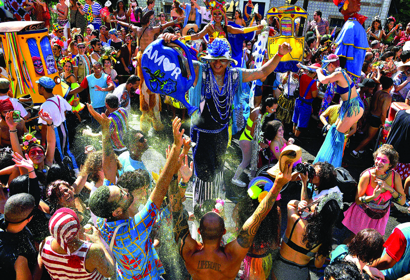 (FILES) In this file photo taken on February 15, 2020 a performer showers revellers with glitter in a street party during the annual 'Ceu Na Terra bloco', in the run up to Rio's carnival, in Rio de Janeiro, Brazil. - Revelers hoping to escape the coronavirus doldrums at Rio de Janeiro's world-famous carnival got more bad news on September 25, 2020 as organizers indefinitely postponed the city's epic street parties, a day after the official parades were scrapped. (Photo by CARL DE SOUZA / AFP)