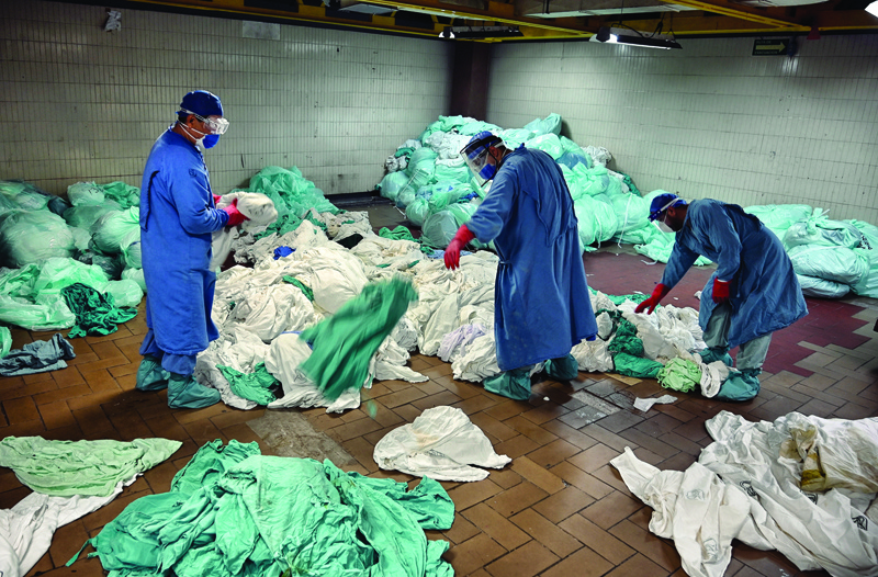 Workers handle dirty laundry from the COVID-19 zone, in the laundry room of the Mexican Institute of Social Security (IMSS), in Mexico City on September 10, 2020. - Cleaning workers also risk their lives in Mexico's pandemic hospitals, knowing that their efforts often go unnoticed. (Photo by ALFREDO ESTRELLA / AFP)