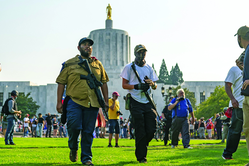 SALEM, OR - SEPTEMBER 7: Far-right protesters walk past the state capitol with long rifles during a rally on September 7, 2020 in Salem, Oregon. A Pro-Trump caravan drove into the Oregon state capitol Monday afternoon where far-right protesters clashed with counter protesters.   Nathan Howard/Getty Images/AFPn== FOR NEWSPAPERS, INTERNET, TELCOS &amp; TELEVISION USE ONLY ==